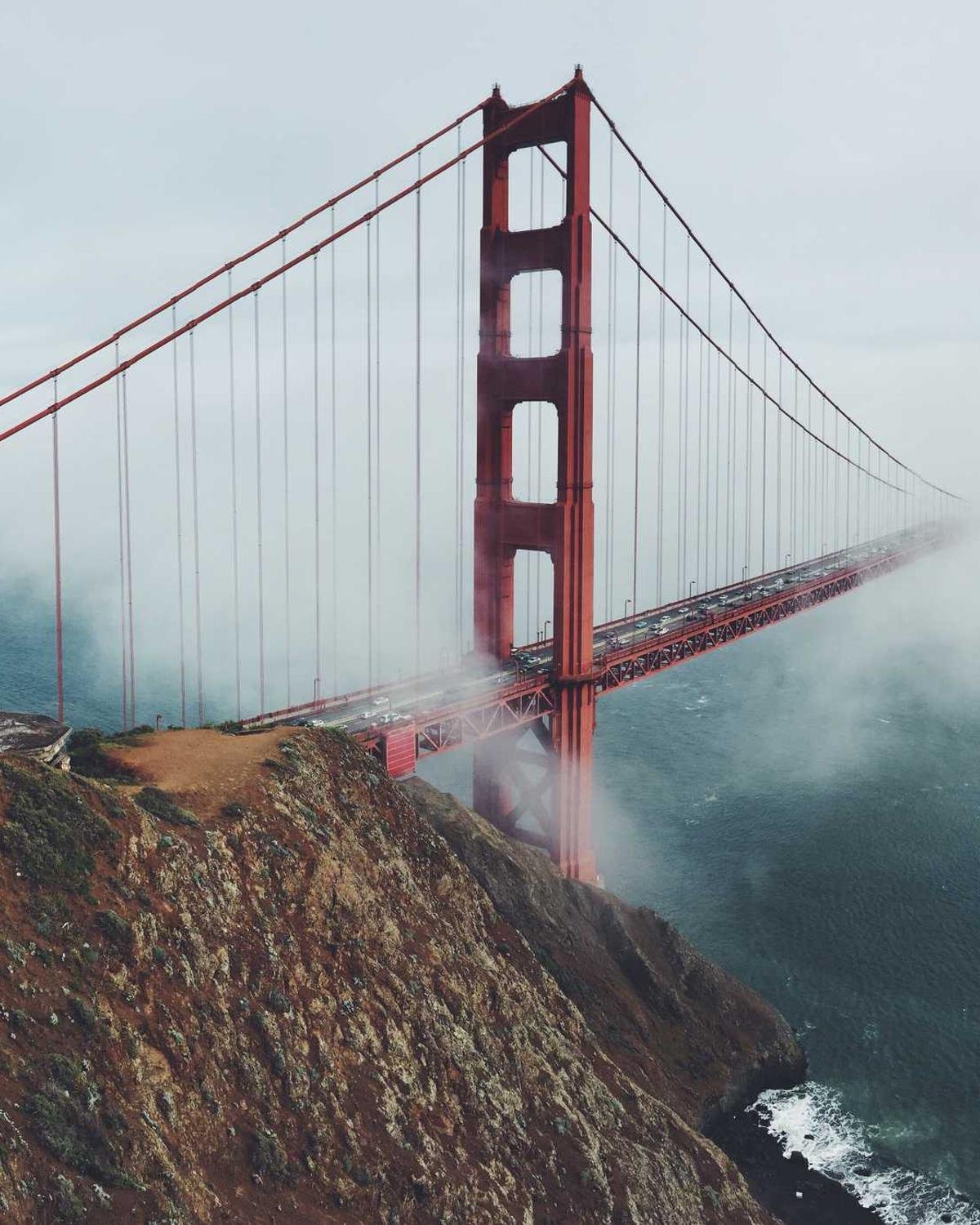 Ponte suspensa atravessa a neblina sobre o mar